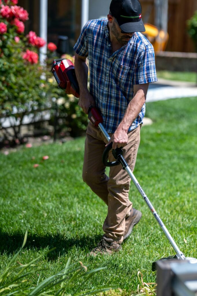 Man edging and weed eating a lawn with a battery powered edger